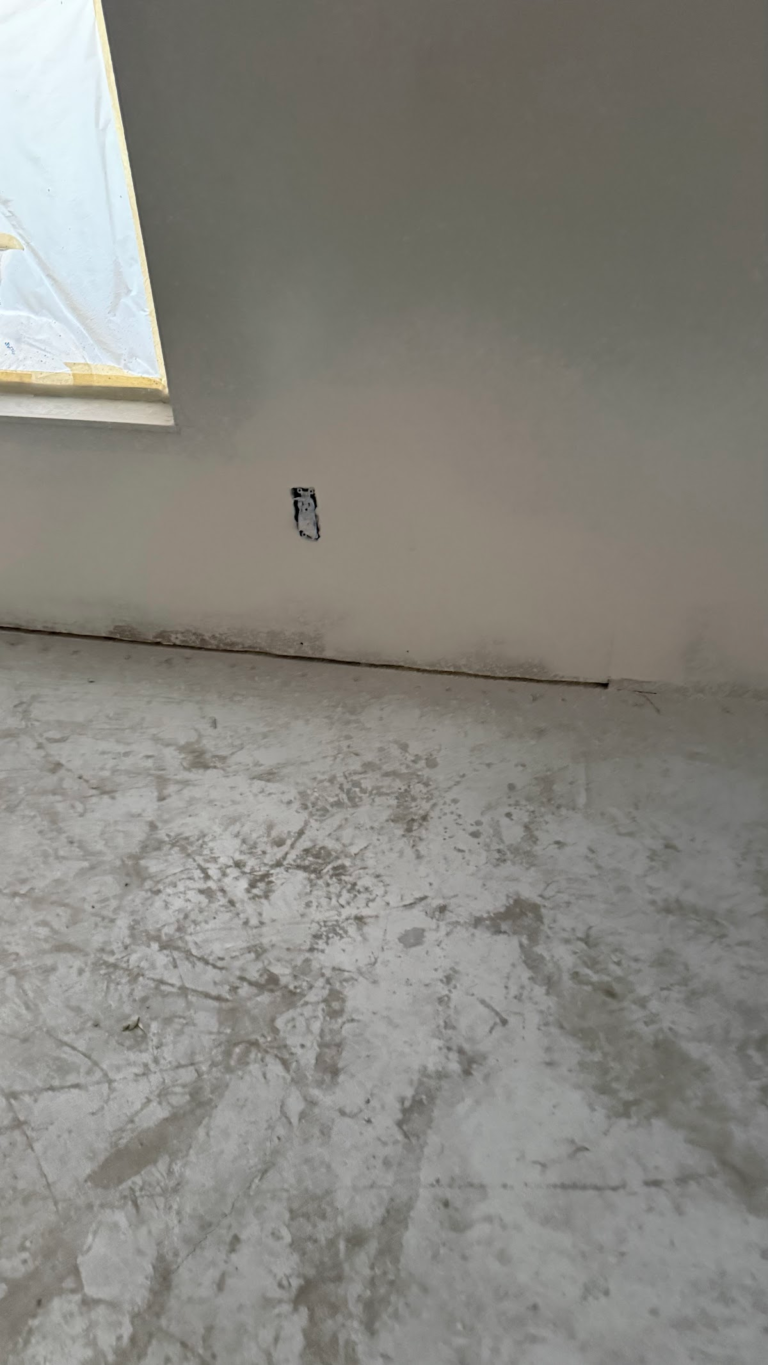 Bare floor preparation beside window during the Las Vegas home restoration project.