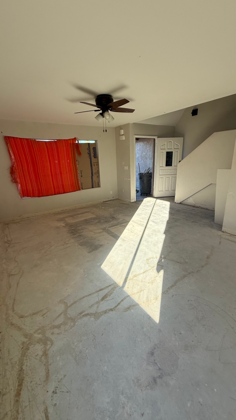Bedroom with ceiling fan and exposed floor during the Las Vegas home restoration project.