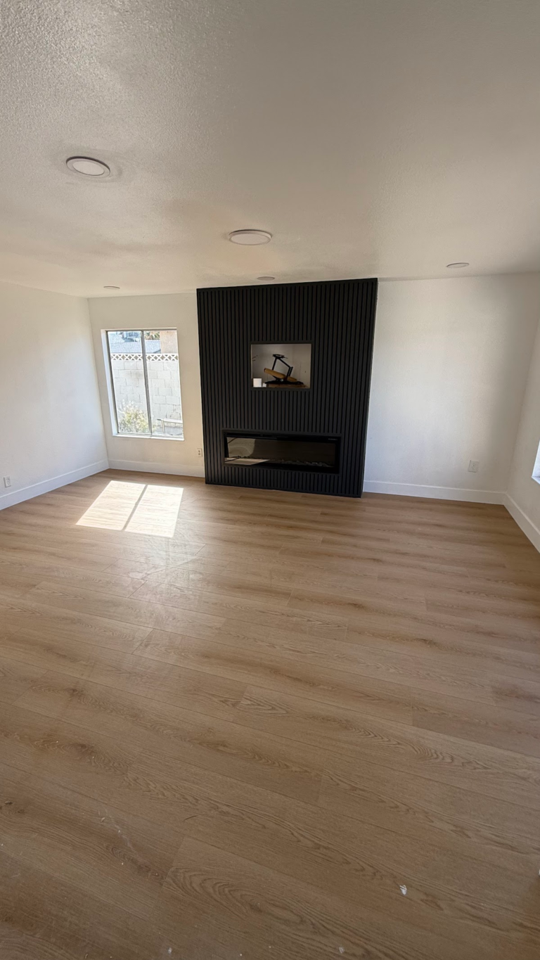 Black fireplace wall and wood-look floor during the Las Vegas home restoration project.
