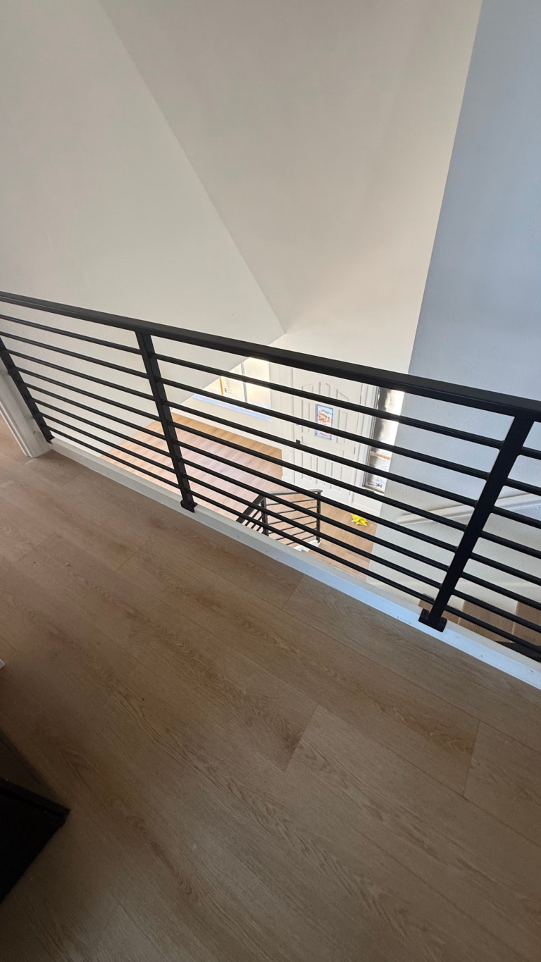 Black stair railing viewed from upper landing during the Las Vegas home restoration project.