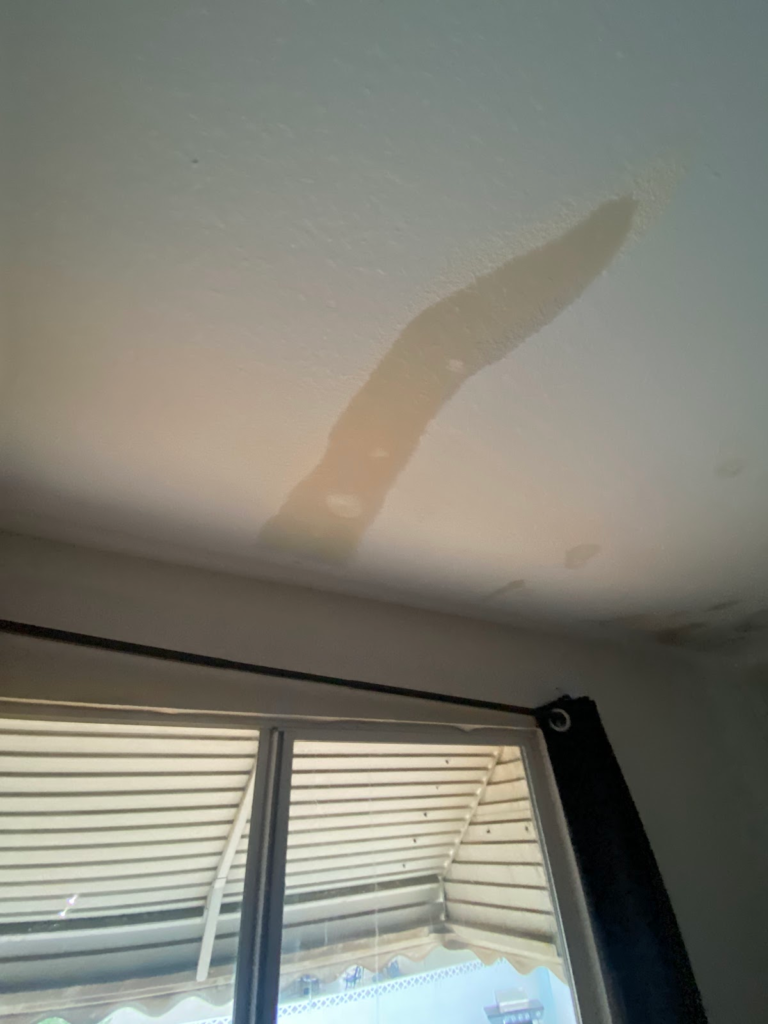 Ceiling water stain beside bedroom window during the Las Vegas home restoration project.