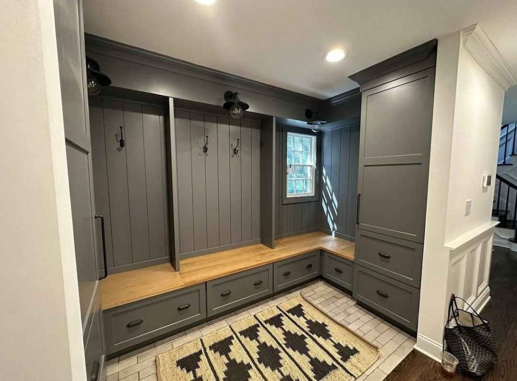 Custom mudroom built-in carpentry with bench seating drawers hooks and tall cabinets