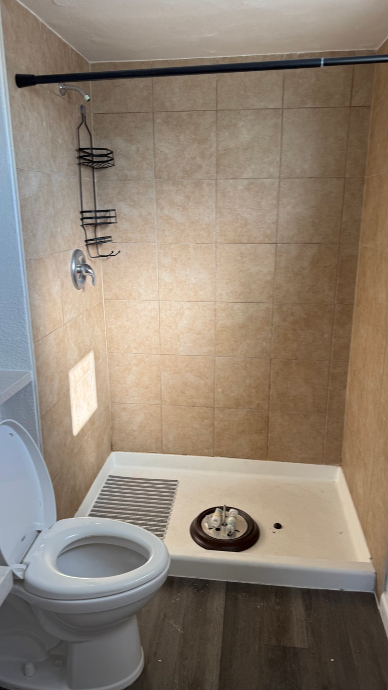 Existing tiled shower and toilet before remodel during the Las Vegas home restoration project.