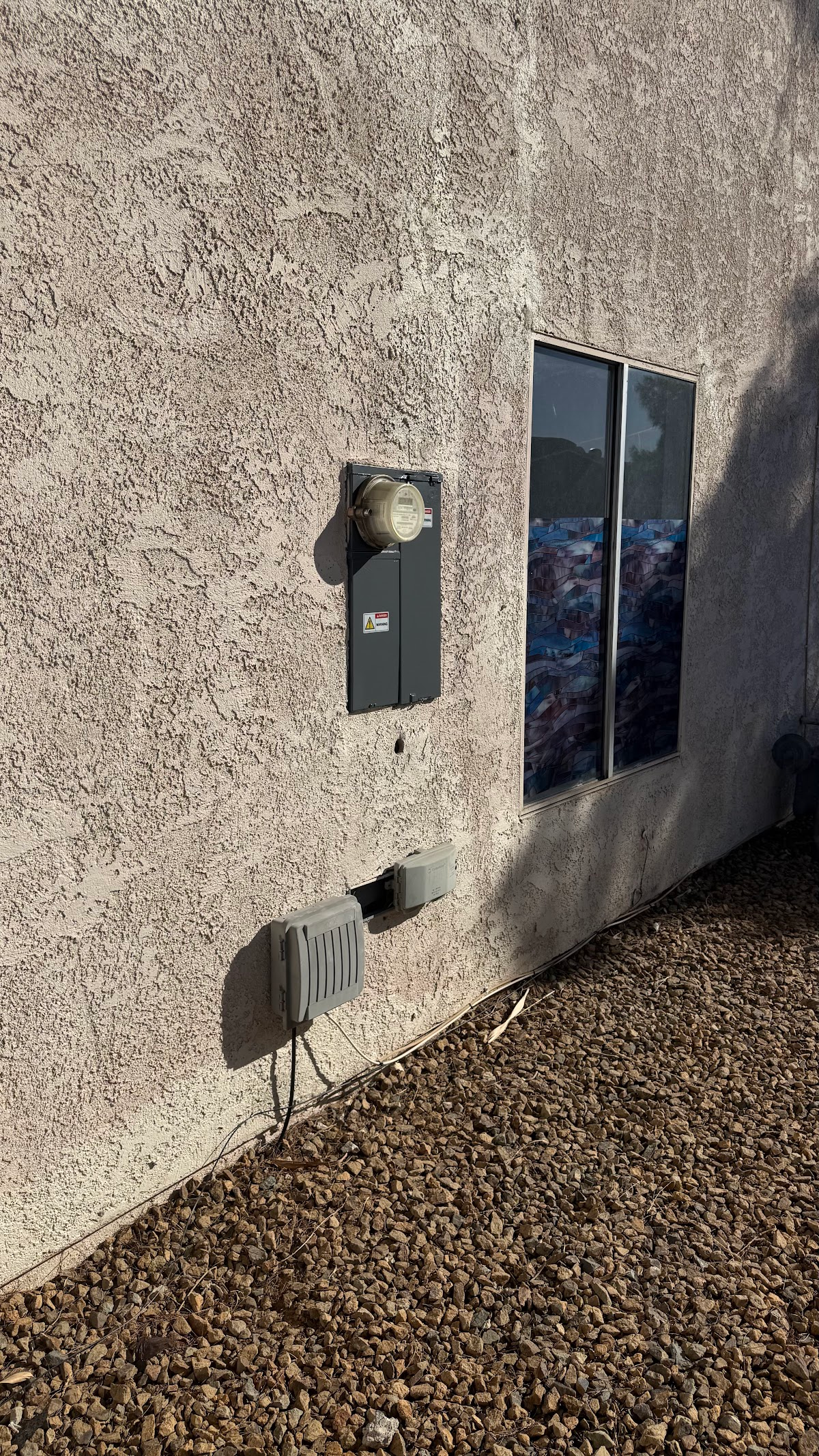Exterior stucco wall beside an electrical service panel
