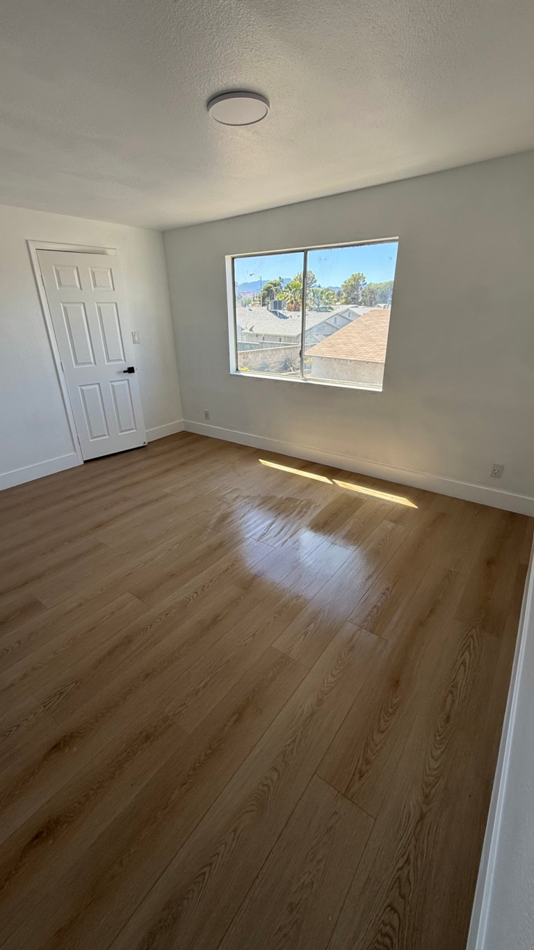 Finished bedroom with sunlit wood-look floor during the Las Vegas home restoration project.