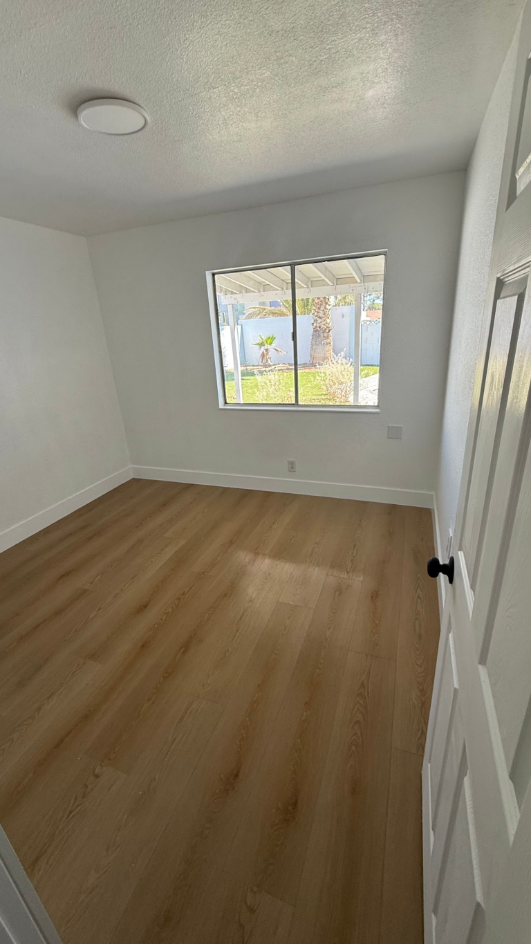 Finished bedroom with window and wood-look floor during the Las Vegas home restoration project.