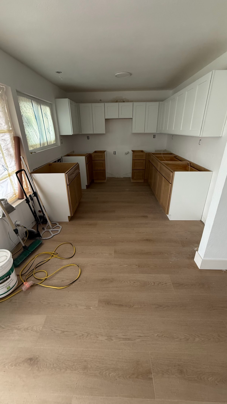 Kitchen cabinet installation with new flooring during the Las Vegas home restoration project.