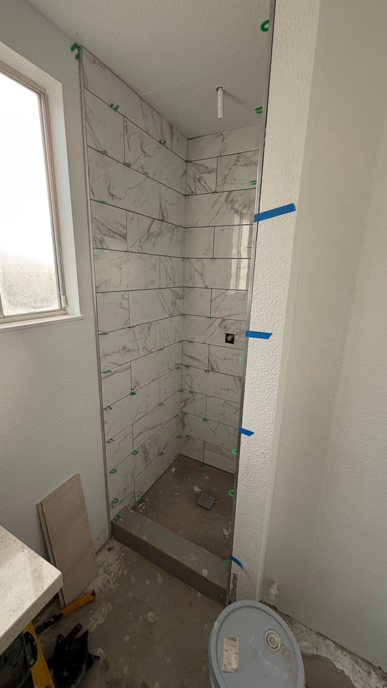 Marble-look shower wall tile installation during the Las Vegas home restoration project.