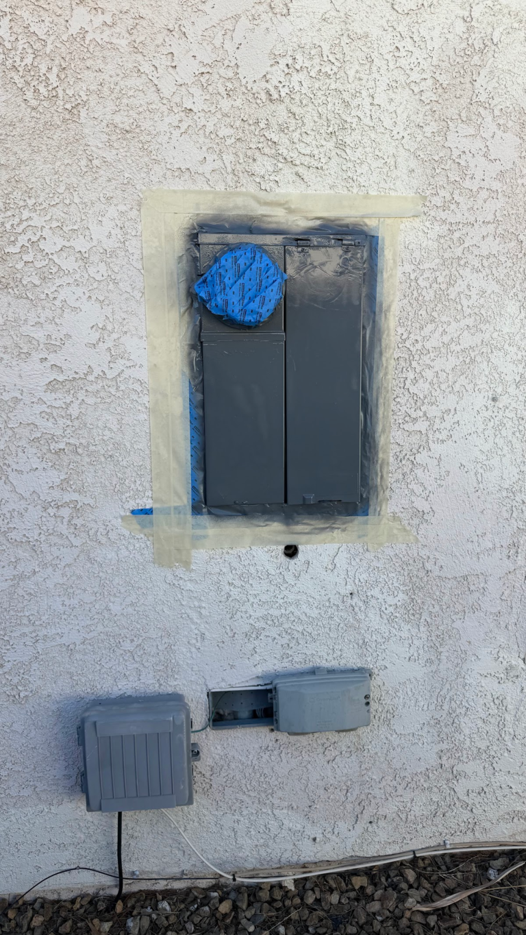 Masked electrical meter area on stucco wall during the Las Vegas home restoration project.