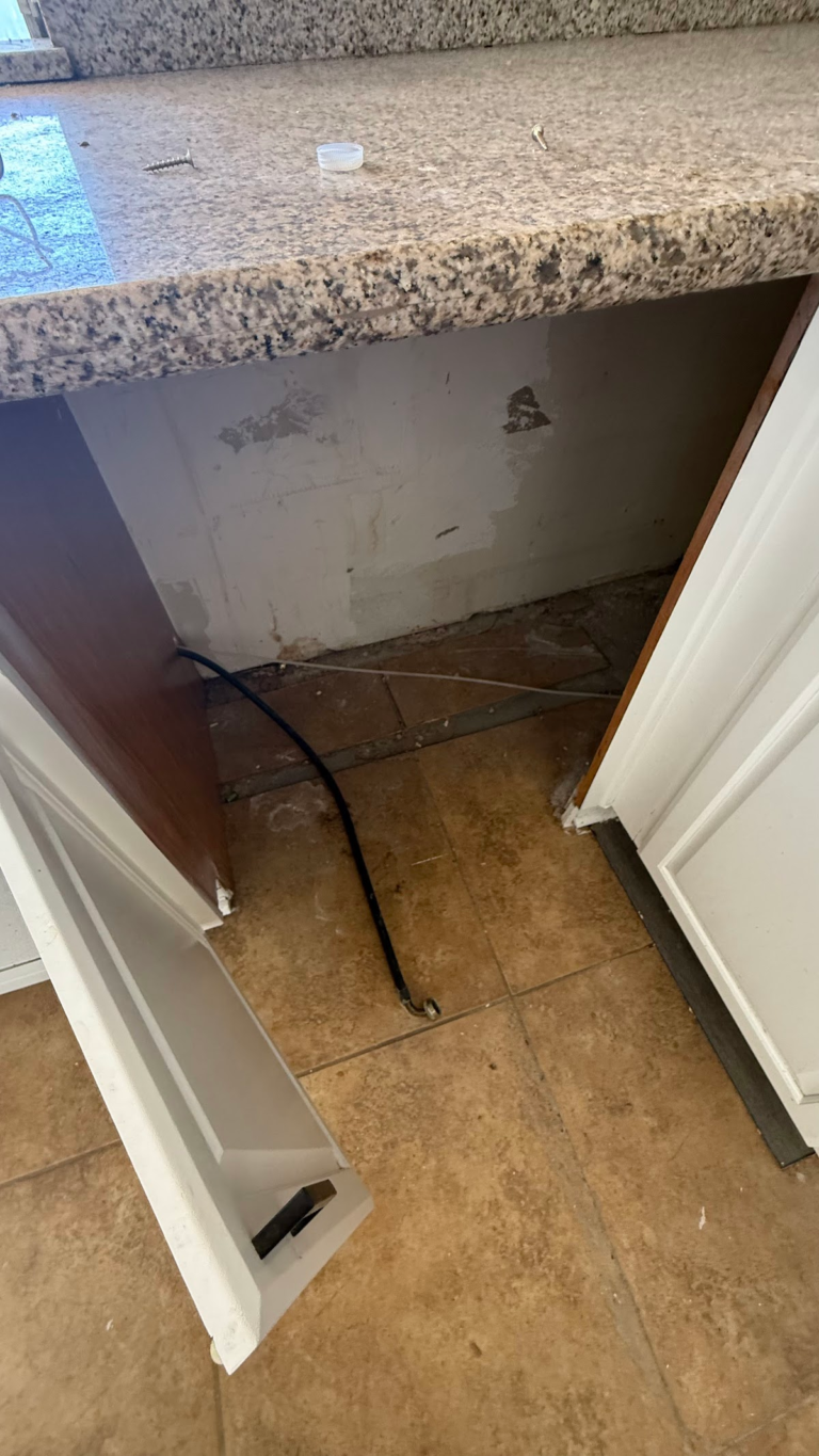 Open sink cabinet with exposed plumbing during the Las Vegas home restoration project.