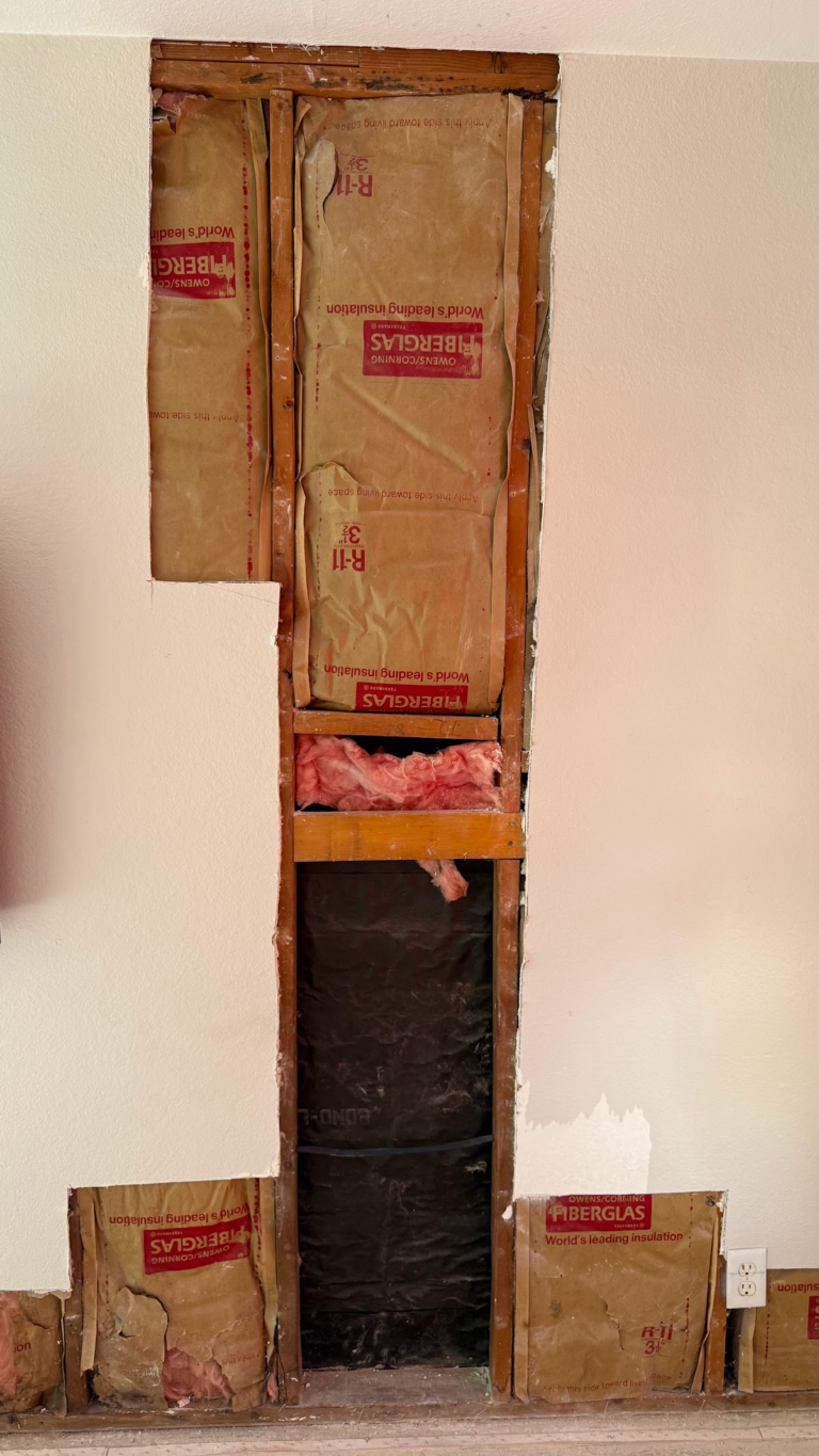 Opened wall exposing framing and insulation during the Las Vegas home restoration project.