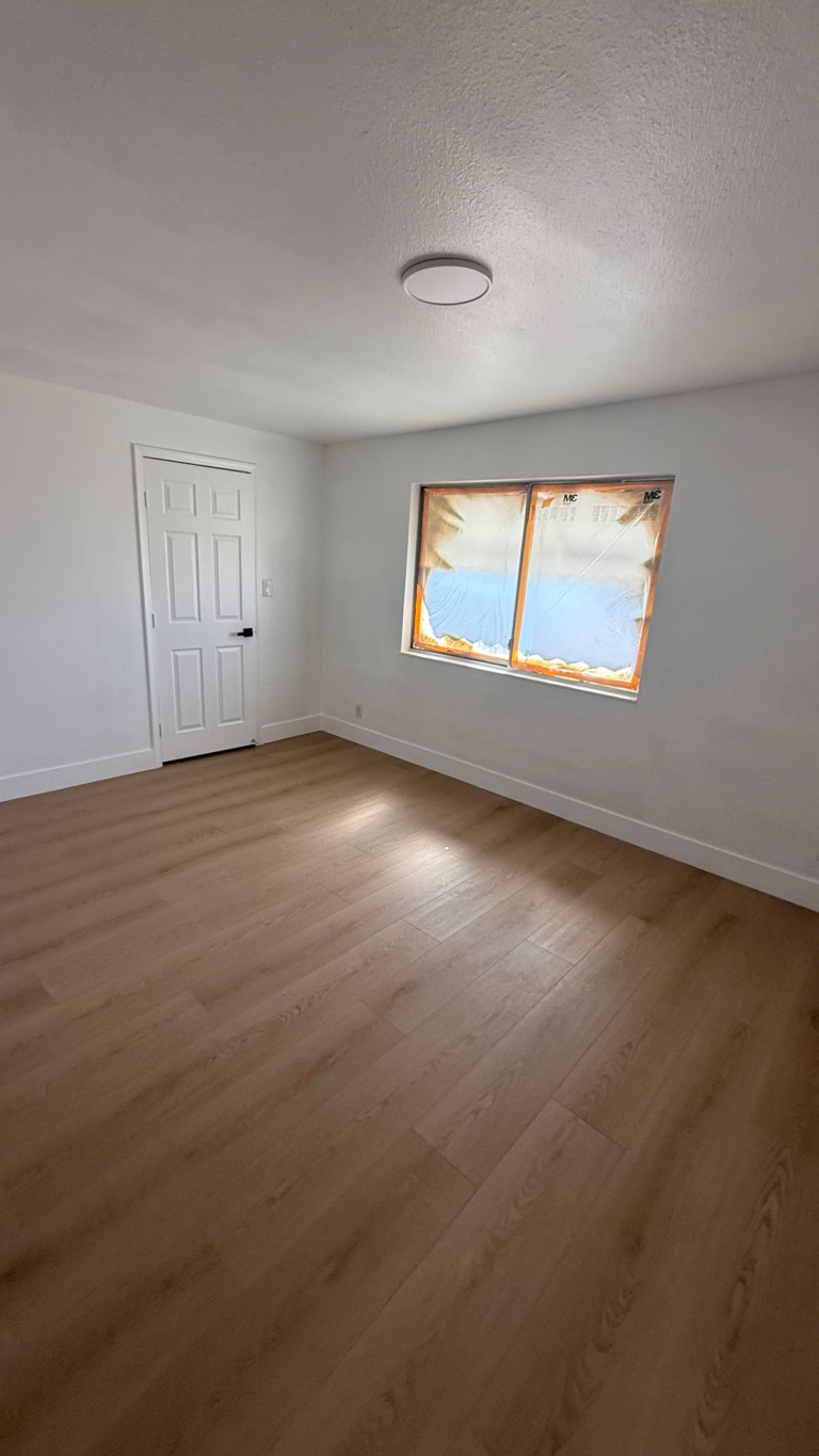 Remodeled bedroom with closet door and window during the Las Vegas home restoration project.