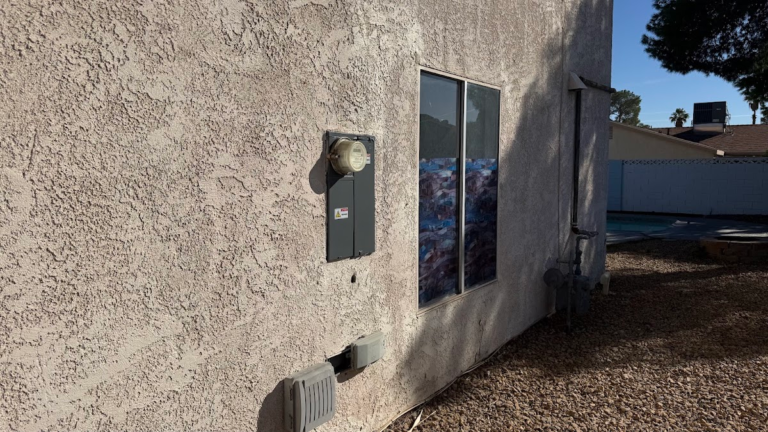Side exterior wall with windows and service equipment during the Las Vegas home restoration project.