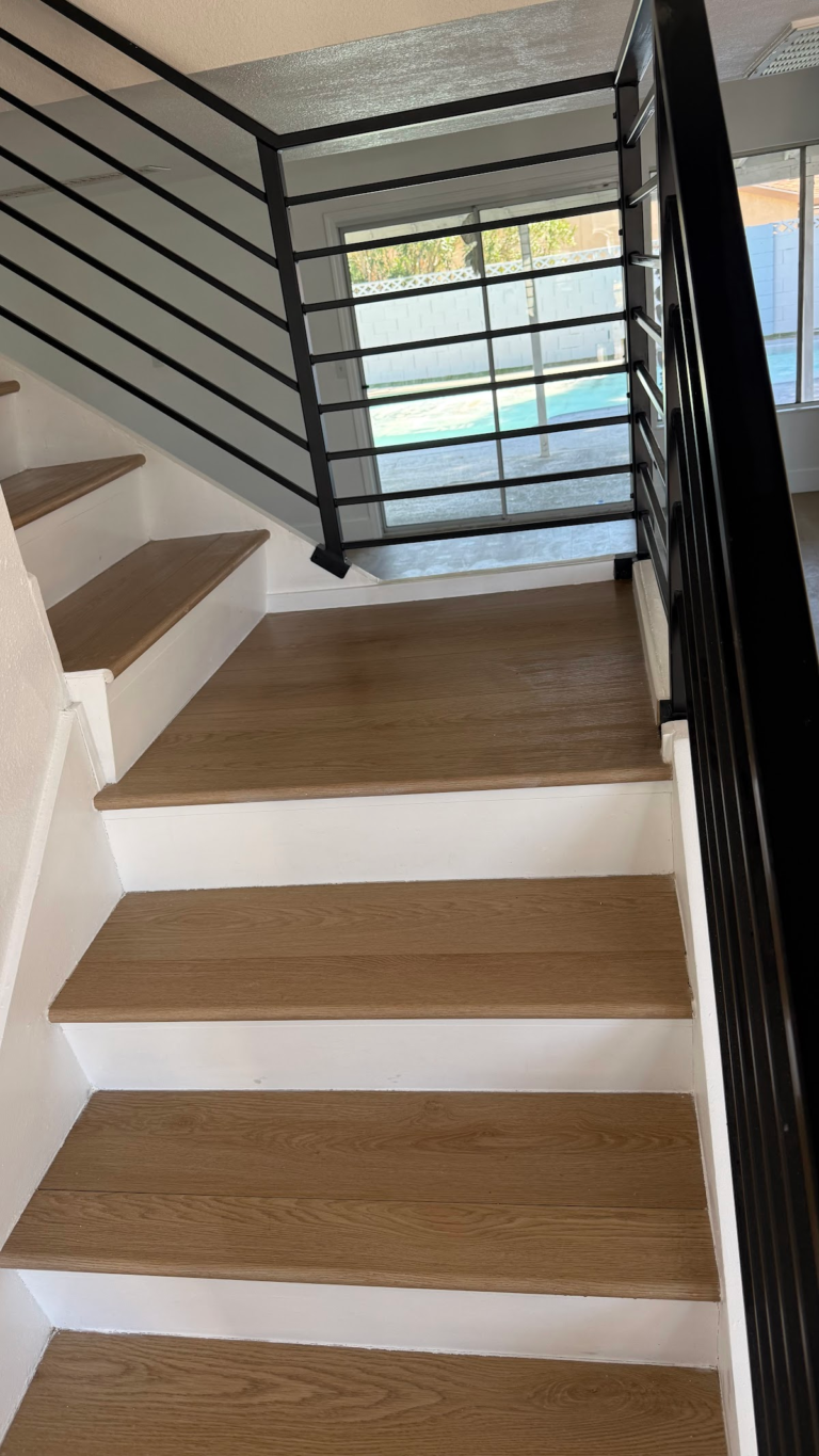 Wood-look stair treads and black metal railing during the Las Vegas home restoration project.
