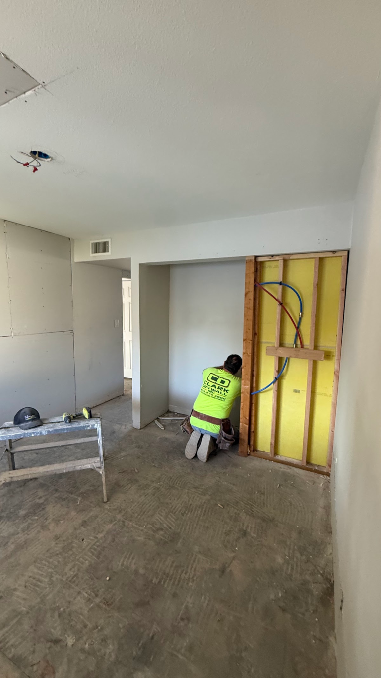 Worker finishing drywall beside wall framing during the Las Vegas home restoration project.