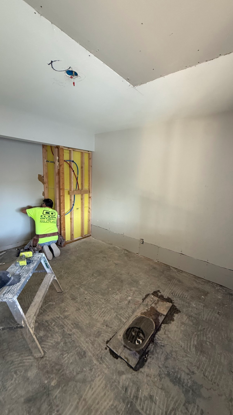Worker finishing wall beside exposed framing during the Las Vegas home restoration project.