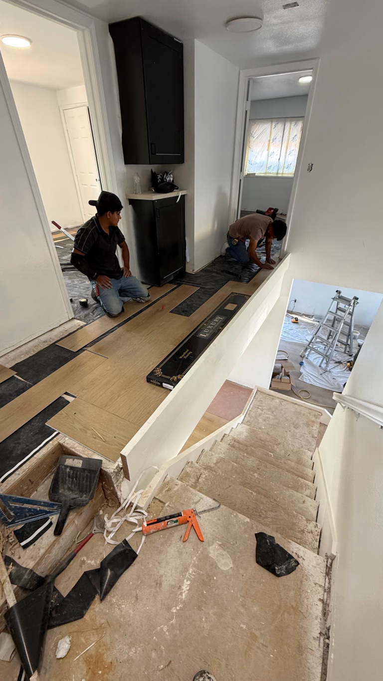 Workers installing flooring around fireplace during the Las Vegas home restoration project.