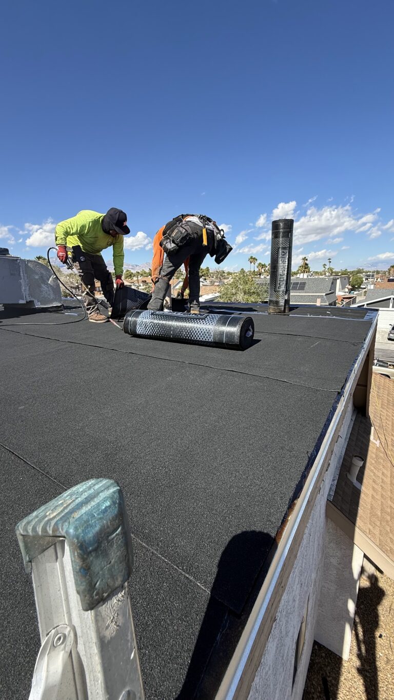 Workers sealing roof membrane around vents during the Las Vegas home restoration project.